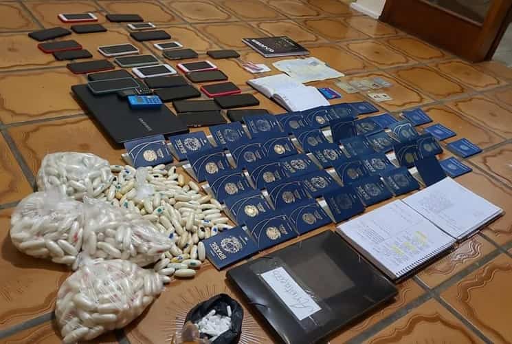 Drogas e passaportes apreendidos em casa onde 33 pessoas eram treinas para engolir capsulas de cocaína — Foto: Divulgação